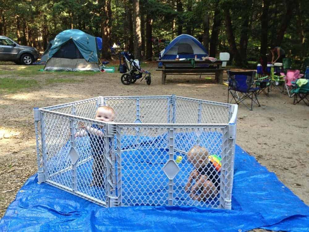 babies playing in playard camping with tarp underneath