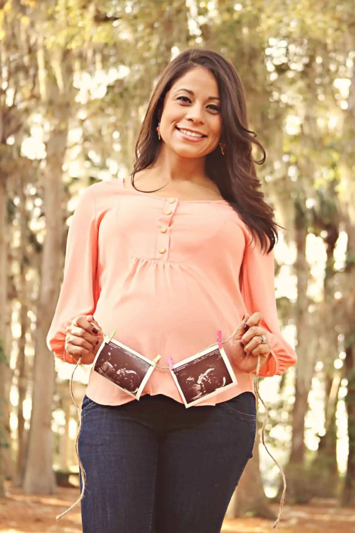woman holding twin sonograms over pregnant belly