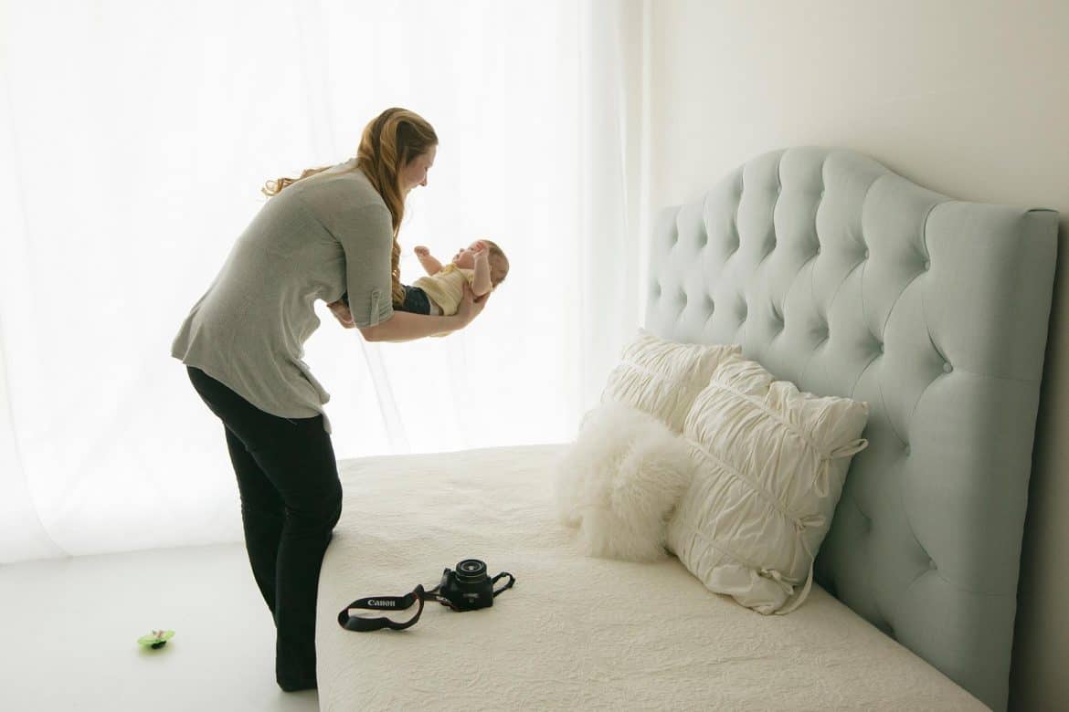 mom doing DIY baby photoshoot with her baby on the bed