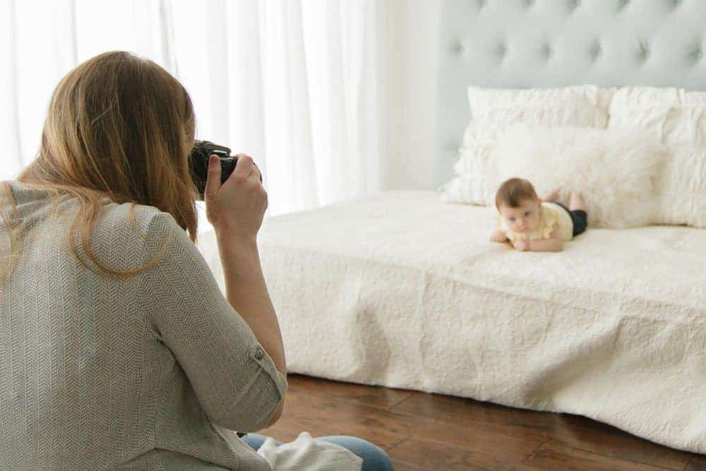 mom taking a picture of her baby on the bed in a DIY baby photoshoot