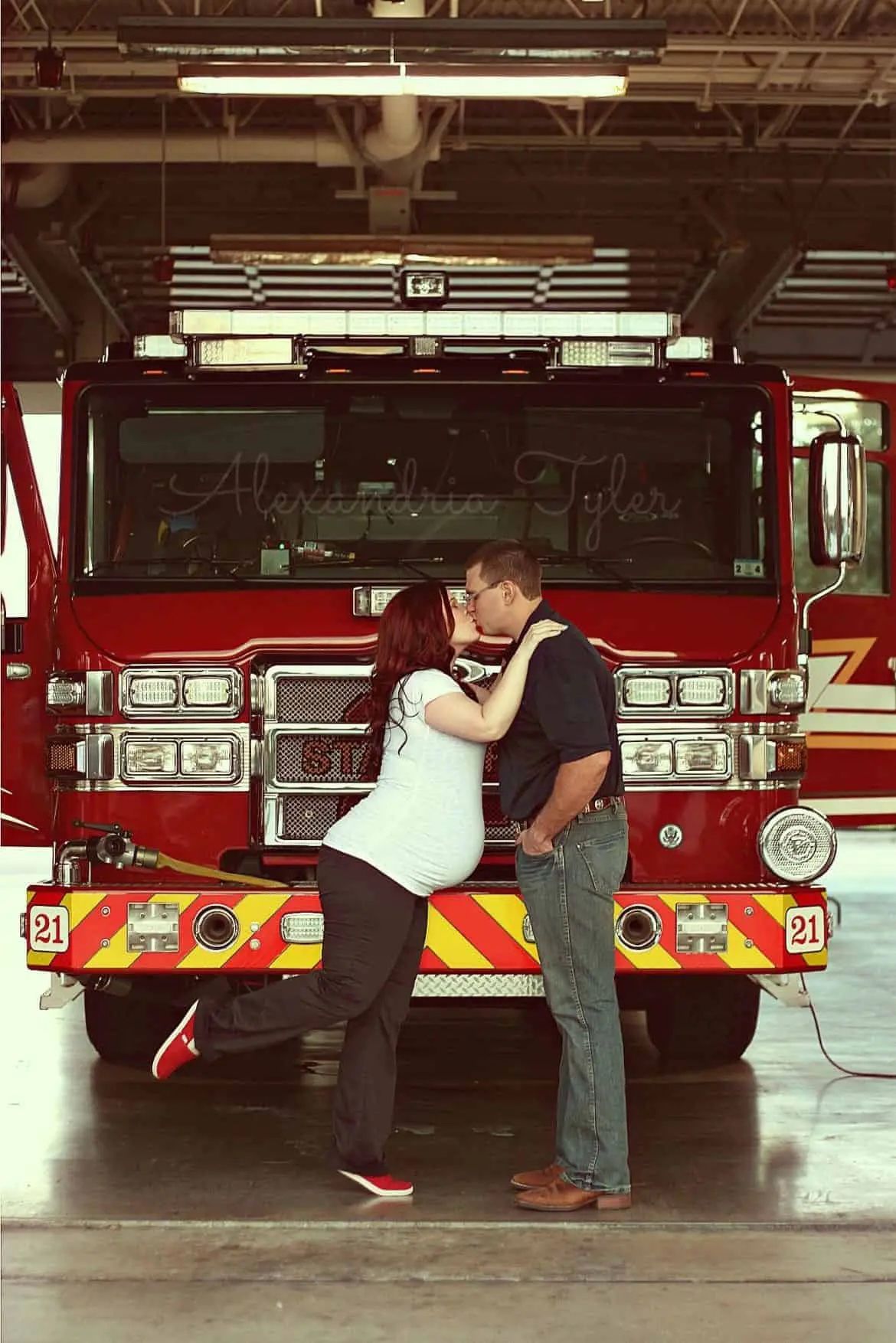 expecting couple kissing in front of fire truck