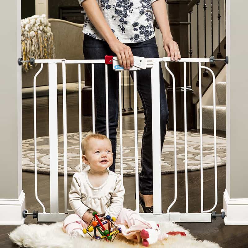 baby playing on one side of a baby gate - things to keep at grandma's house