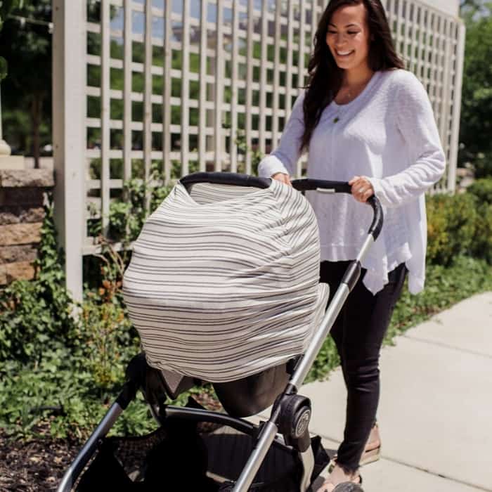 woman pushing baby stroller with car seat cover