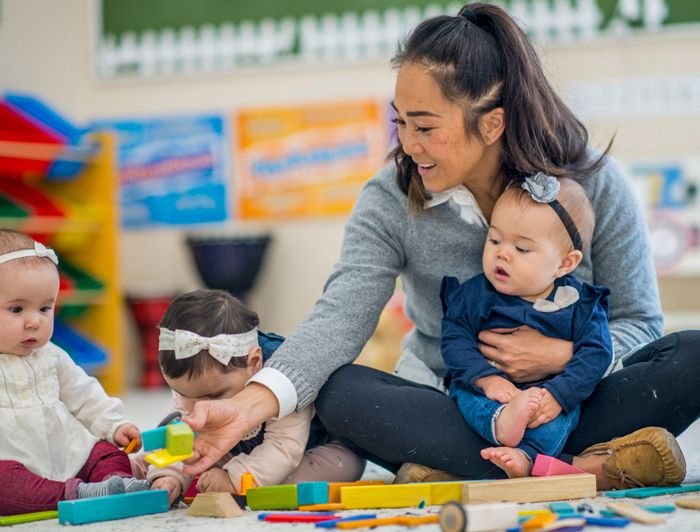 woman in her home daycare holding a baby on her lap