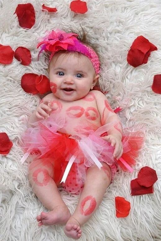 Baby laying on floor surrounded by rose petals with kiss marks on their body