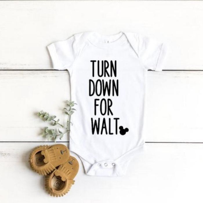 White newborn onesie with black letters that say "turn down for Walt"