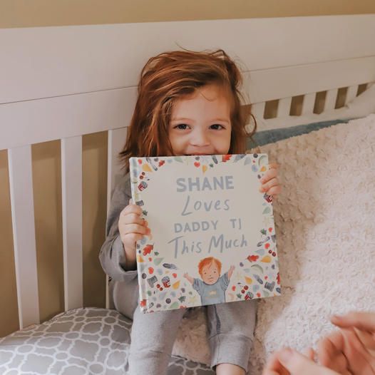 child holding a custom 'dad' book for father's day.