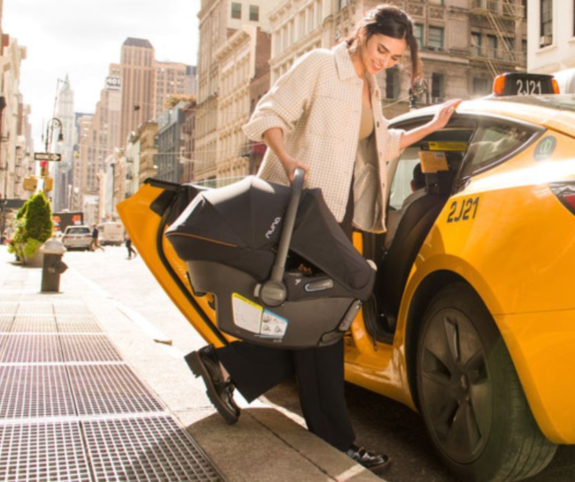 woman loading PIPA urbn carseat into a taxi