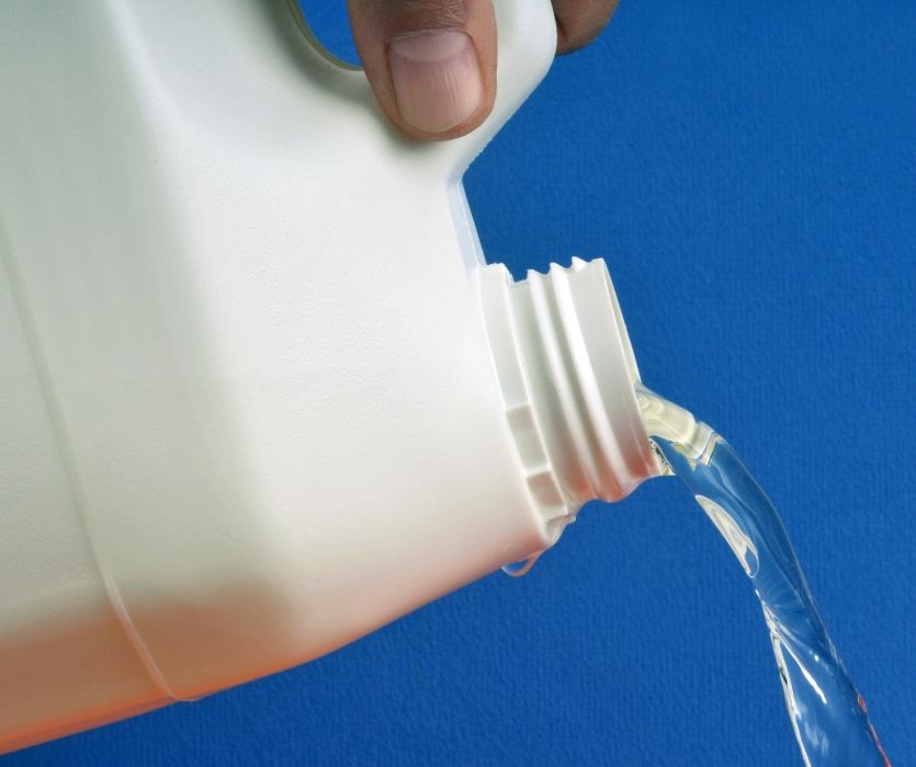 hand pouring cleanser out of white jug
