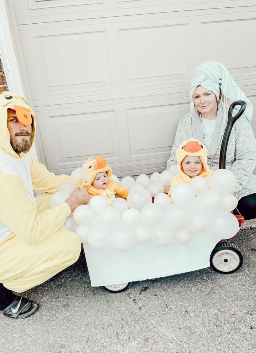 siblings in duck costumes sitting in a wagon made to look like a bubble bath